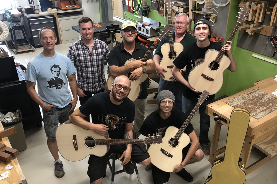 students showing off their completed guitars