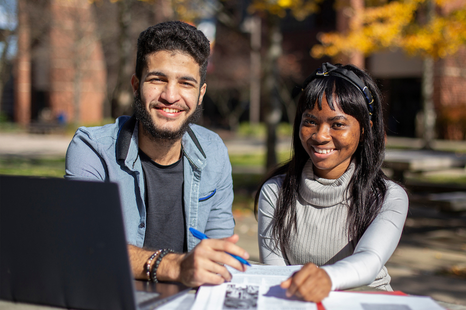 Two international students sitting at a laptop